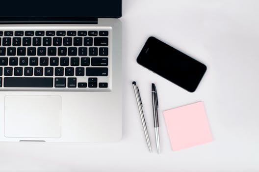 pexels-photo-296114-296114 Overhead view of a sleek workspace featuring a laptop, smartphone, and stationeries on a white desk.